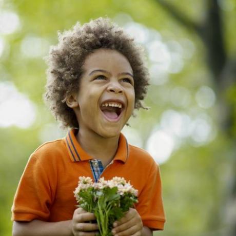 Chlapec (3-5) drží květinu, směje se