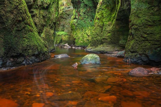 Krev červená řeka v zelené rokli. Devil's Pulpit, Finnich Glen, poblíž Killearn, Skotsko, Velká Británie