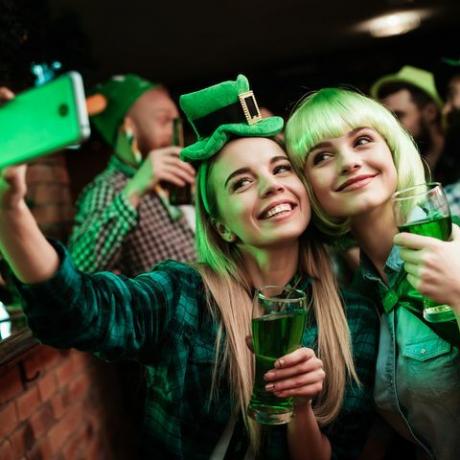 Dvě dívky v paruku a čepici se u baru dělají selfi.