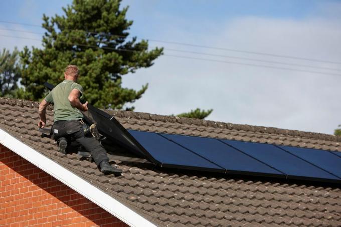 h0chn1 muž instalující pole střešních solárních panelů v domácí instalaci solárních panelů ve Velké Británii
