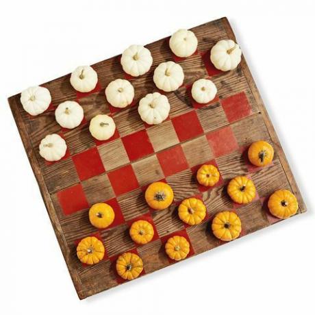 dřevěná deska malovaná jako hra dáma pomocí mini dýní v bílé a oranžové barvě jako hrací kusy