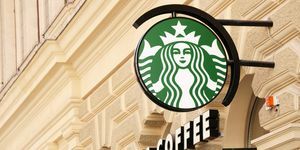 Vídeň, Rakousko 1. května 2012 zelené logo kávy Starbucks na sloupu a text kávy Starbucks na fasádě starý dům v centru Vídně diagonálně fotografoval zaměření na logo starbucks je známý pro velké jít káva