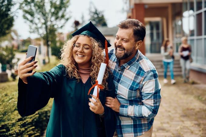 šťastná absolventka univerzity a její otec se baví při pořizování selfie s chytrým telefonem