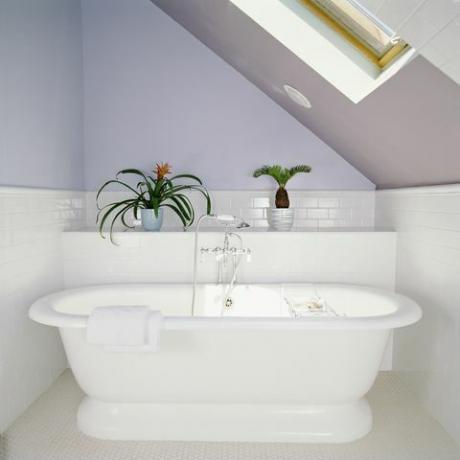 vana pod světlíkem v podkrovní koupelně s lila fialovými stěnami