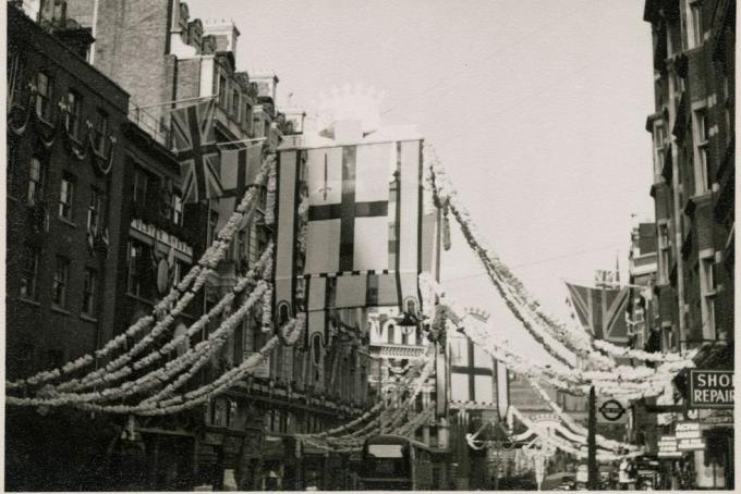 fleet street, city of london, větší londýnská autorita, 1953 pohled na vlajky visící na budovách a v centru fleet street, z nichž jsou navlečeny dekorace, např. korunovace alžběty ii. korunovace alžběty ii. se konala 2. června 1953 vlajky visící podél středu ulice flotily na této fotografii jsou vlajkou město londýn, které se vyznačuje červeným mečem v levé horní čtvrtině kříže svatého Jiří, umělec jr uppington photo by historic englandheritage images via getty snímky