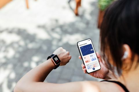 mladá žena pomocí aplikace fitness tracker na chytrých hodinkách a smartphonu