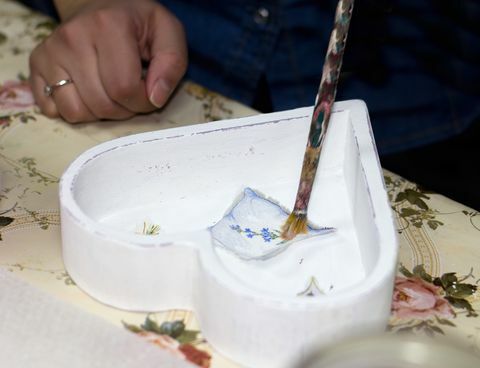 ruční řemeslník maloval vystřižený obrázek s lepidlem na vnitřní straně bílé krabice ve tvaru srdce