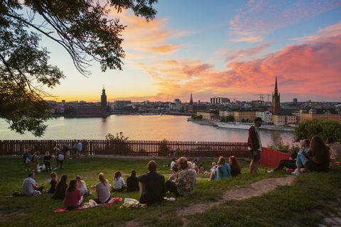 Lidé mají piknik v parku s panorama Stockholmu při západu slunce, Švédsko