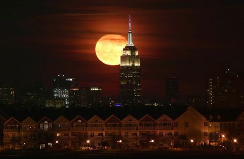 Úplněk se tyčí za Empire State Building v New Yorku